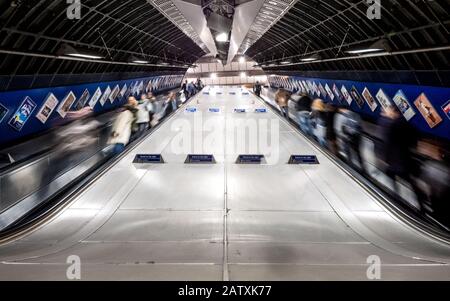 La metropolitana di Londra. Esposizione a lungo la sfocatura del tubo treno viaggiatori e pendolari utilizzando le scale mobili presso la trafficata Stazione della metropolitana di London Bridge. Foto Stock