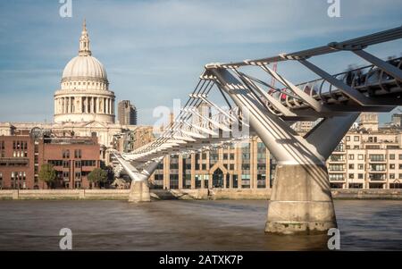 Lunga esposizione che offusca l'acqua del Tamigi come scorre sotto il Millennium Bridge che conduce verso la cattedrale di San Paolo in lontananza Foto Stock