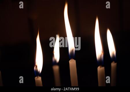 La candela si illumina nel buio. Sfondo candele astratto. Speranza, fuoco. Foto Stock