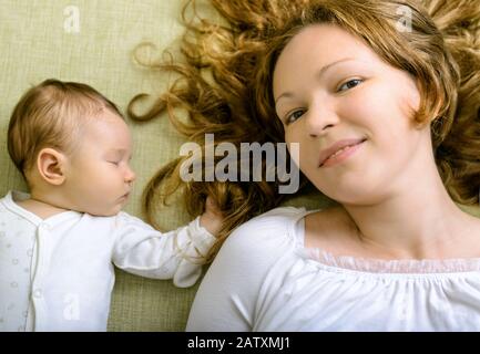 Bella donna e sua figlia appena nata sul divano a casa Foto Stock