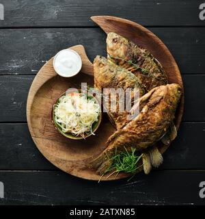 Pesce di carpa fritto in un piatto di legno. Piatti di pesce. Vista dall'alto, spazio libero per il testo. Stile rustico. Foto Stock