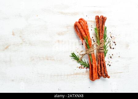 Salsiccia secca con rosmarino su fondo bianco legno. Kabanosy. Vista dall'alto. Spazio libero per il testo. Foto Stock