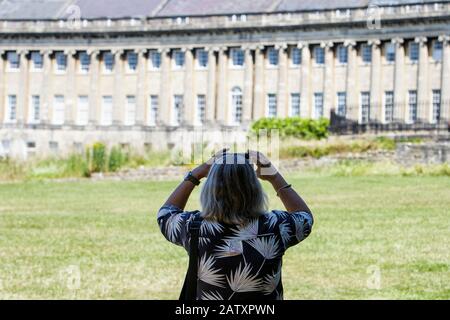 Bath, Inghilterra. Una donna è raffigurata mentre prende una fotografia del Royal Crescent a Bath, Somerset, Inghilterra, Regno Unito Foto Stock