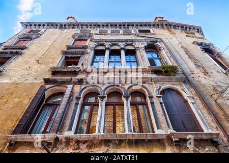 Vecchia casa a Venezia, Italia. Vista ad angolo basso di un antico edificio residenziale. Facciata d'epoca della casa storica da vicino. Vecchia architettura Di Ve Foto Stock