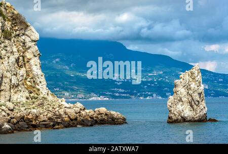 Costa rocciosa nel Mar Nero, Crimea, Russia. Città di Yalta in lontananza. Paesaggio della Crimea in estate. Vista panoramica sulle scogliere del Southe Foto Stock