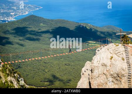 Crimea, RUSSIA - 19 MAGGIO 2016: Passeggiata turistica sul ponte di corda sul Monte ai-Petri. Ai-Petri è una delle montagne più alte in Crimea e turistico a. Foto Stock