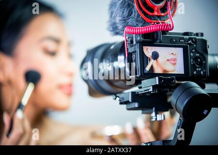 Bella giovane donna fare make-up dalla fotocamera, make-up tutorial. Foto Stock