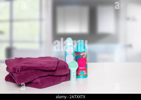 Piano del tavolo sullo sfondo degli asciugamani. Primo piano di asciugamani da bagno in spugna morbida fresca con sapone e shampoo bottiglia sul tavolo su sfondo bagno sfocato. Spazio. Foto Stock