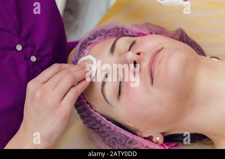 Salviettine estetiste viso del cliente sul divano con batuffoli di cotone. Foto Stock