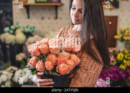 Donna fiorista tiene un grande bouquet bello di rose rosa fiorite in un negozio di fiori Foto Stock
