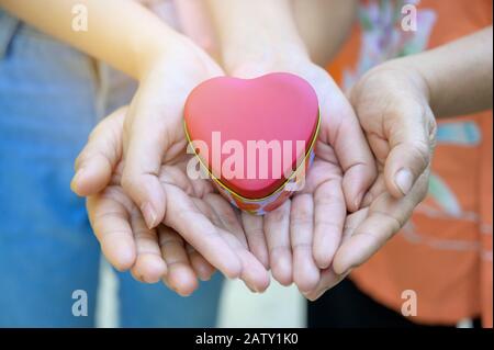 Le mani dei bambini e degli adulti nella famiglia hanno un cuore nelle loro mani. Foto Stock