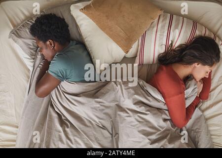 Giovane coppia multietnica sdraiata sul letto e dormendo in camera da letto Foto Stock