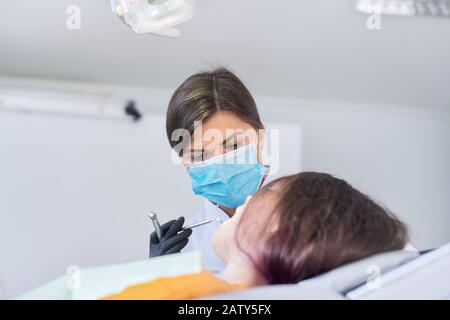 Ragazza giovane che tratta i denti, adolescente femminile seduto in sedia dentisti. Odontoiatria, denti sani, medicina e concetto di assistenza sanitaria Foto Stock