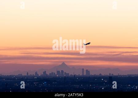 Bergamo, Italia - 5 febbraio 2020: Un aereo parte dall'aeroporto di Orio al Serio vicino Bergamo. Sullo sfondo una vista sullo skyline di Milano con la vetta del Monviso (3841m) sullo sfondo, a più di 150 miglia di distanza. L'Italia è stata spazzata da gales e raffiche di vento, che misurano fino a 160 km/h, eliminando l'aria dall'inquinamento e dalla polvere atmosferica credito: Piero Crociatti/Alamy Live News Foto Stock