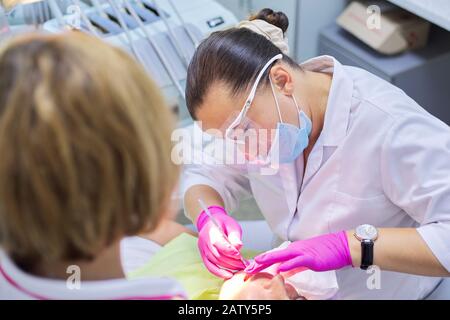 Medico dentista con assistente che cura i denti ad un paziente in clinica dentale. Odontoiatria, denti sani, sedazione, medicina e concetto sanitario Foto Stock