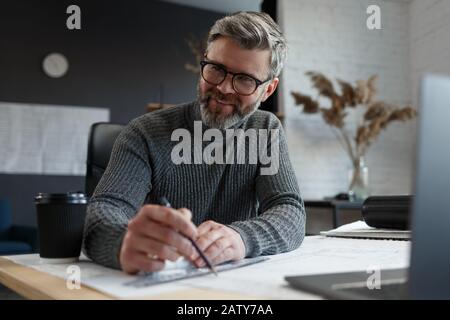 Interior designer che lavora in ufficio con blueprints.Engineer ispezionare il piano architettonico, disegnando un progetto di costruzione.Ritratto di bel bearded Foto Stock