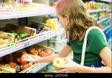 Bella bambina che sceglie le mele nel supermercato. Foto Stock