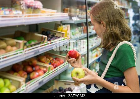 Bella bambina che sceglie le mele nel supermercato. Foto Stock