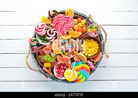 Caramelle colorate, gelatina e marmellata in una scatola di legno. Dolci. Sul vecchio sfondo. Vista dall'alto. Spazio di copia libero. Foto Stock