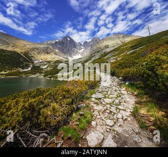 Vista della cima di Lomnica in alta Tatra e una strada intorno ad un lago di montagna, Slovacchia Foto Stock