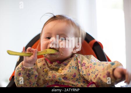 bambina di 8 mesi che mangia cibo Foto Stock