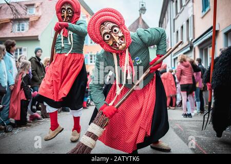La strega Kandel di Waldkirch, bella strega in blu e rosso lentamente si avvicina e si appoggia sulla scopa. Durante la sfilata di carnevale a Staufen, a sud Foto Stock