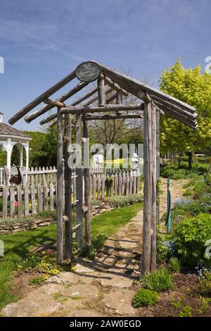 Sentiero in pietra attraverso il vecchio arbour in legno nel giardino rustico cortile con recinzione in primavera Foto Stock