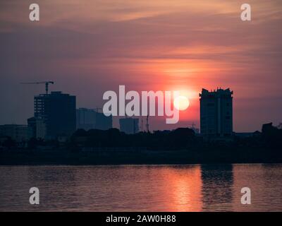 Un tramonto fumoso sopra le gru di costruzione di Phnom Penh, Cambogia Foto Stock