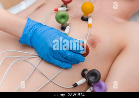 Cardiogramma del cuore. Il medico collega gli elettrodi di un elettrocardiografo al torace del paziente. Cardiologia Foto Stock