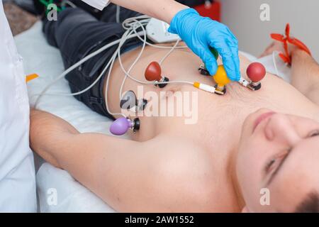 Cardiogramma del cuore. Il medico collega gli elettrodi di un elettrocardiografo al torace del paziente. Cardiologia Foto Stock