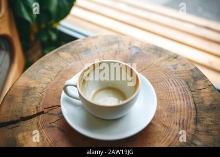 Tazza vuota dopo aver bevuto del caffè su di un tavolo di legno. Concetto per la fine di una riunione o qualcos'altro. Foto Stock