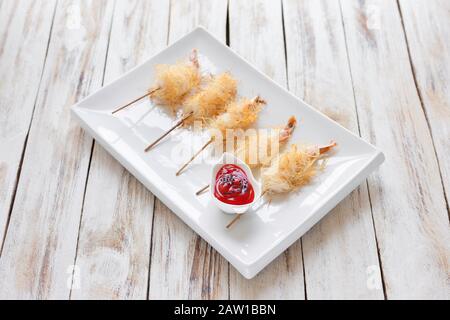 Gamberi croccanti avvolti in pasta Kataifi chiamato anche Kanafeh, Kadaif. Servito con salsa su vecchio sfondo bianco di legno. Foto Stock