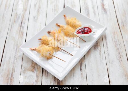 Gamberi croccanti avvolti in pasta Kataifi chiamato anche Kanafeh, Kadaif. Servito con salsa su vecchio sfondo bianco di legno. Foto Stock
