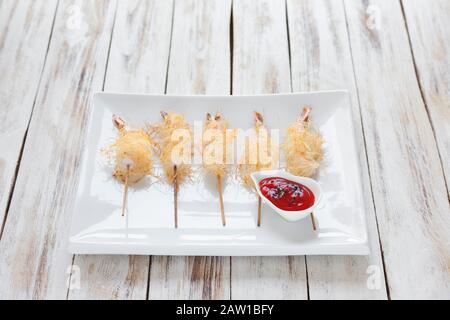 Gamberi croccanti avvolti in pasta Kataifi chiamato anche Kanafeh, Kadaif. Servito con salsa su vecchio sfondo bianco di legno. Foto Stock