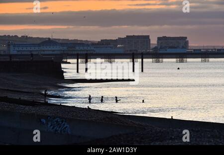 Brighton UK 6th Febbraio 2020 - i nuotatori del mattino presto si avventurano nel mare per un tuffo freddo mentre il sole sorge sul lungomare di Brighton. Più bel tempo stabilito è previsto per la prossima coppia di giorni in Gran Bretagna prima che il tempo tempestoso è impostato per arrivare durante il fine settimana . Credito: Simon Dack / Alamy Live News Foto Stock