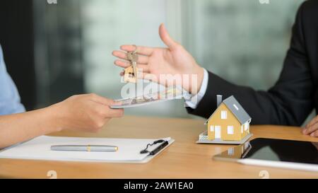 Vista ravvicinata dell'agente immobiliare che dà la chiave della casa al cliente mentre costumer che dà i soldi all'agente Foto Stock