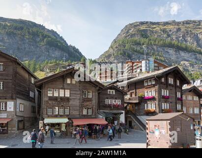 Zermatt, Canton Vallese, Svizzera, settembre 2017: I turisti passeranno accanto ai negozi di vecchi edifici in legno su Oberdorfstrasse, nella città di Zermatt. Foto Stock