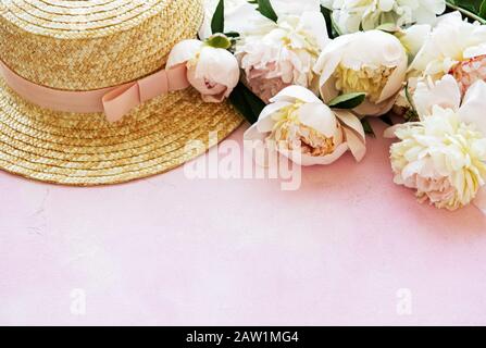 Estate vacanze sfondo. Peonie rosa e il cappello di paglia Foto Stock