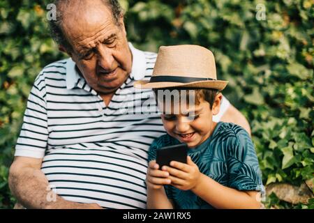 Nonno e nipote che giocano con un telefono cellulare Foto Stock