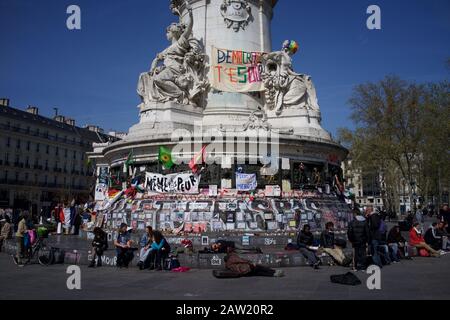 Persone sedute su gradini della statua di Marianne di fronte ai messaggi per ricordare le vittime degli attacchi di Parigi e Bruxelles, Place de la République, Parigi, Francia - aprile 2016 Foto Stock