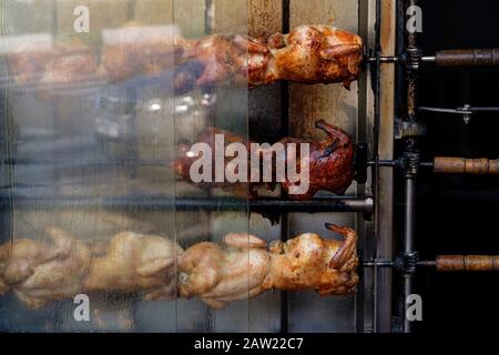 Una torrefazione di pollo chiamata 'Rotisserie' ed i polli in tre file che stanno rotolando e ottenendo arrostiti e cucinati in questo grande forno. Foto Stock