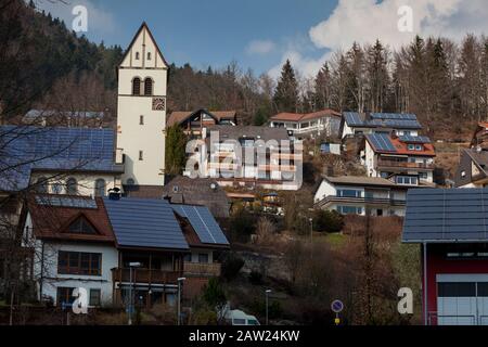 I collettori solari sui tetti e il tetto della chiesa nella comunità della Foresta Nera di Schönau Germania vicino a Titisee generano una gran parte dei bisogni energetici della comunità. Foto Stock