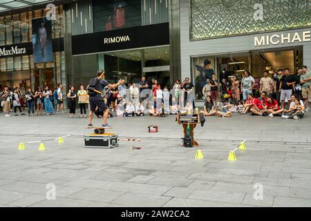 Singapore. Gennaio 2020. Un giocoliere di strada si esibisce su un marciapiede di Orhard Road davanti a un pubblico di bambini Foto Stock