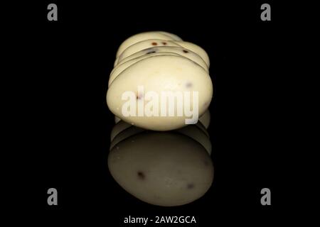 Lotto di stracciatella di mandorla bianca rivestita intera isolata su vetro nero Foto Stock