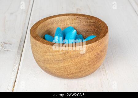 Lotto di gomma da masticare blu intero in ciotola di bambù su legno bianco Foto Stock