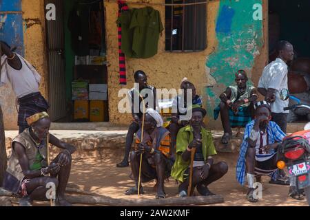 Turmi, Etiopia - Nov 2018: Uomini della tribù Hamer con bastone tradizionale seduti davanti all'edificio. Valle di Omo Foto Stock