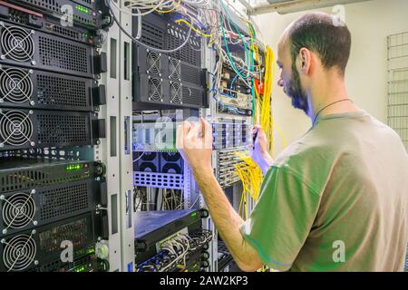 Installazione di un server di database in un rack con apparecchiature informatiche. Il tecnico esegue il lavoro di sostituzione dell'apparecchiatura server. Manutenzione di Foto Stock