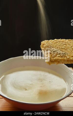 noodle istantanei che si gocciolano all'acqua calda con fumato sul piatto Foto Stock