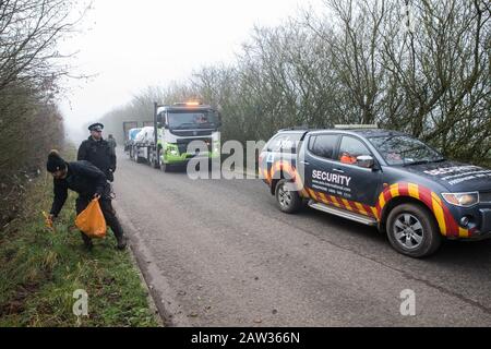 Denham, Regno Unito. 6 Febbraio 2020. Un attivista della ribellione dell'estinzione raccoglie rifiuti mentre i colleghi attivisti ambientali bloccano un veicolo di sicurezza e un camion che fornisce recinzioni e altri materiali da utilizzare per le opere associate al collegamento ferroviario ad alta velocità HS2 vicino al fiume Colne a Denham Ford. Credit: Mark Kerrison/Alamy Live News Foto Stock