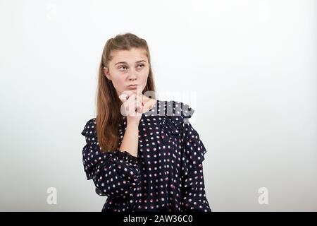 ragazza in un abito nero pensa prende la decisione di tenere il mento con la mano Foto Stock